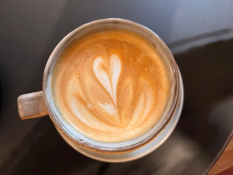 Trendy coffee cup with muted colours, foamed milk in heart shape, close-up, quiet luxury